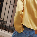 Model wearing yellow cropped silk blazer with notch lapels and blue jeans — By Keara | Endless UAE