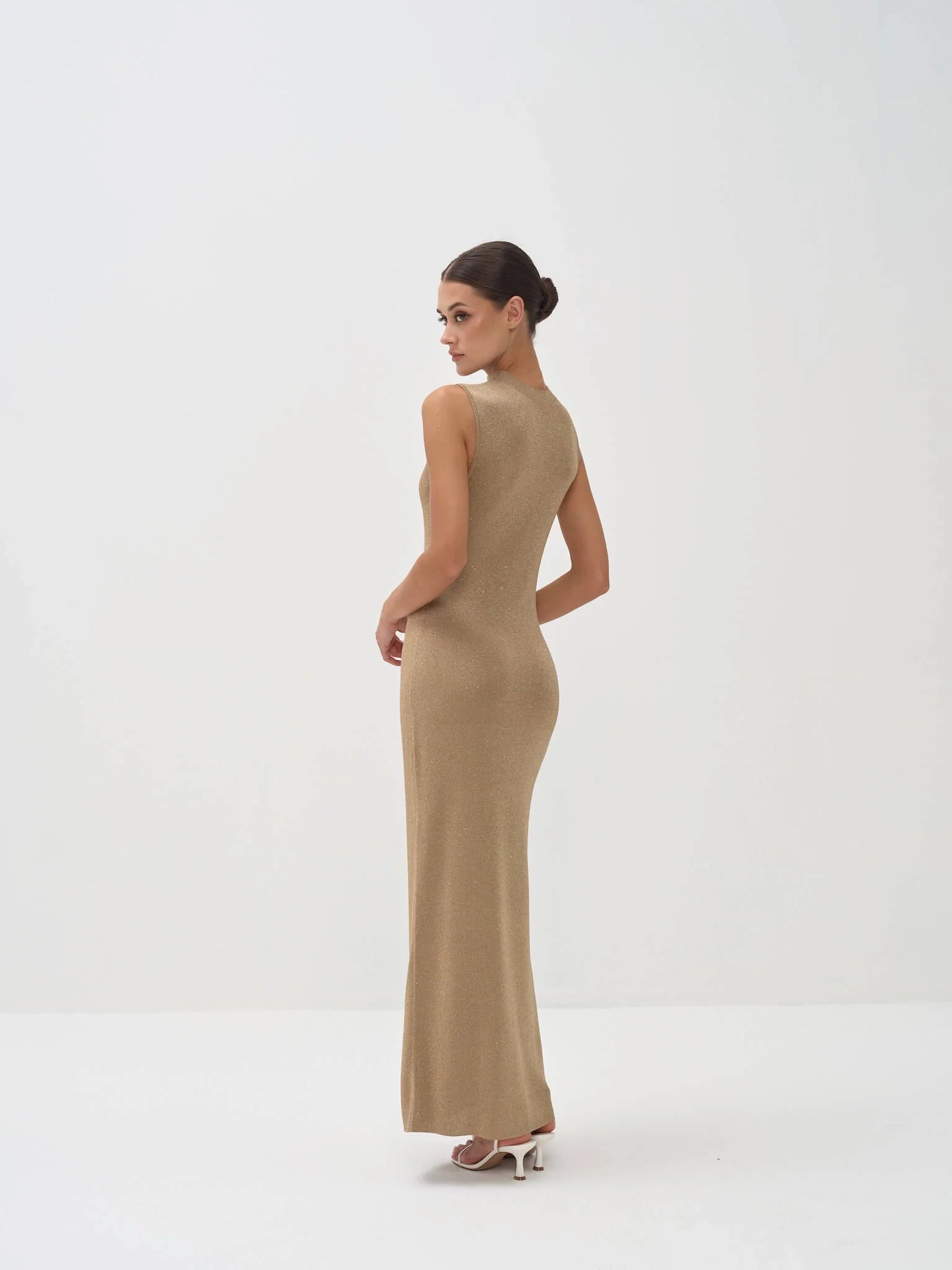 Elegant gold sleeveless maxi dress with form-fitting silhouette, shown from back on model with hair in bun — Nora The Label | Endless UAE