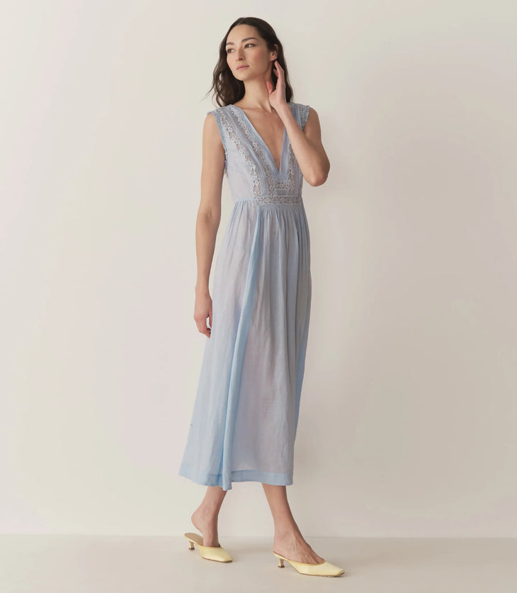 Woman wearing light blue Victoria Midi Dress with lace bodice and cream cardigan — Doen | Endless UAE
