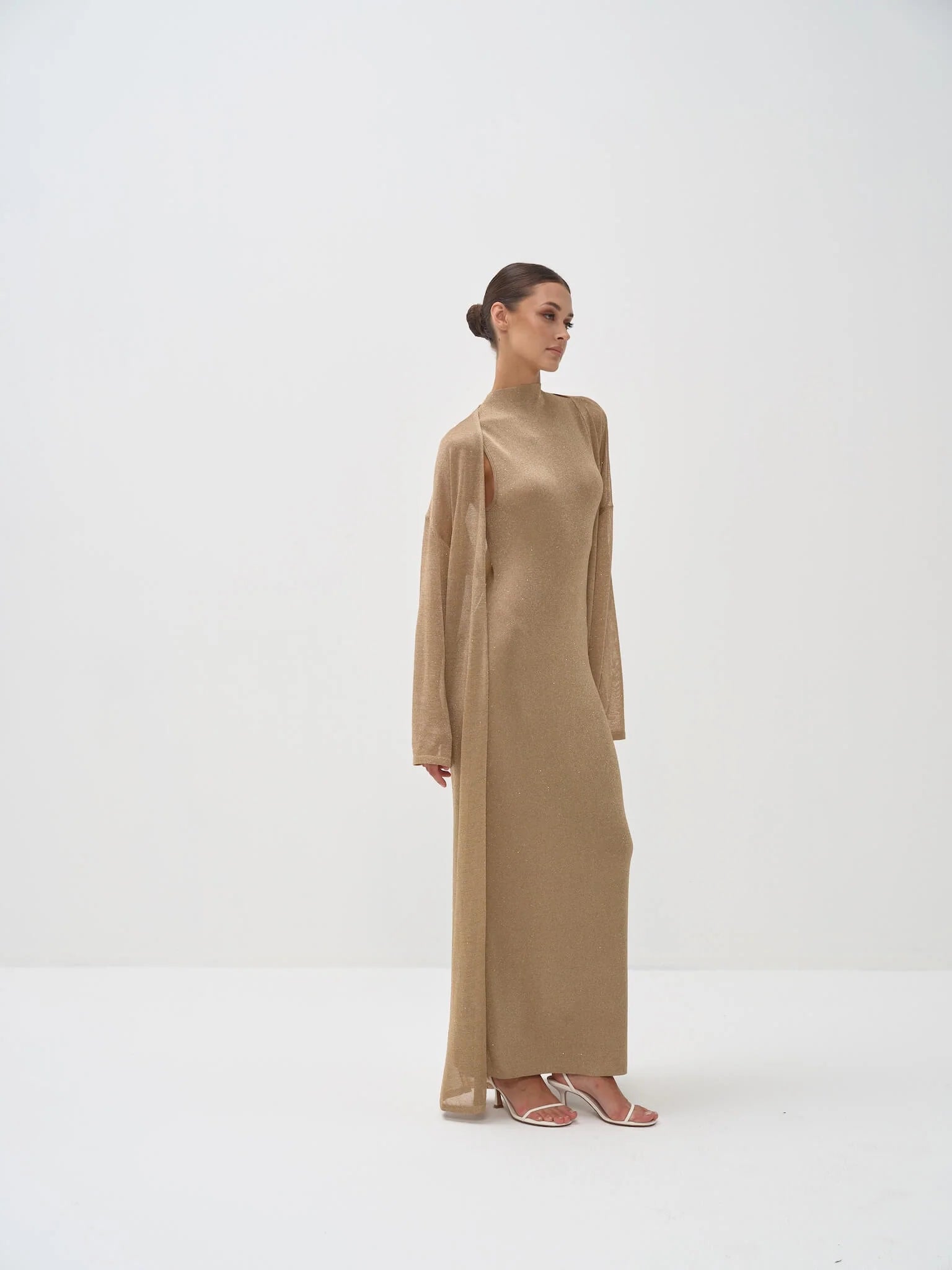 Gold shimmer maxi dress with mock neck and dramatic cape sleeves, worn with strappy heels — Nora The Label | Endless UAE