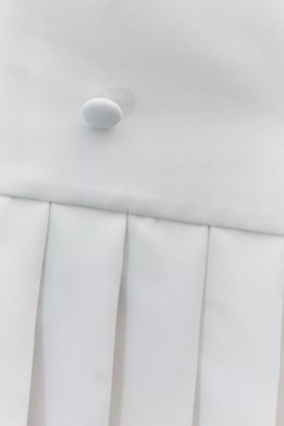 White mini dress with pleated skirt and button detail on white background — Amanda Uprichard | Endless UAE