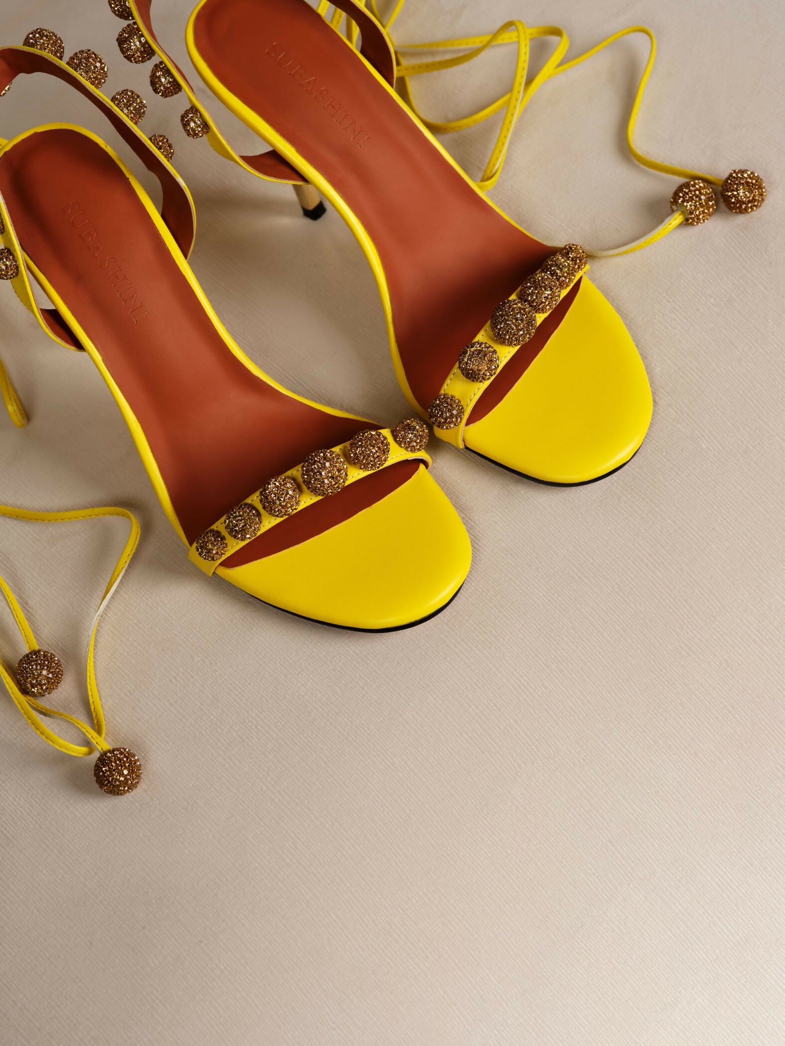 Bright yellow strappy heels with gold glitter embellishments and ankle ties — Subashini Heels | Endless UAE