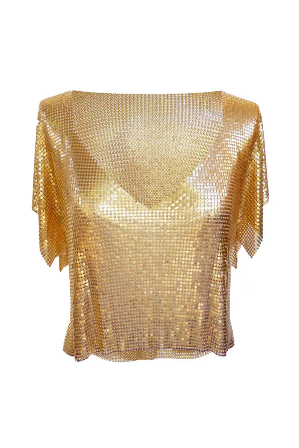 Woman wearing gold sequin Ava Top with denim shorts and black boots on rocky beach — Isabel Moore | Endless UAE