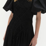 Woman wearing black Wisteria Cotton Midi Dress with puffed sleeves and asymmetrical hem — Aje | Endless UAE