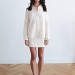 Woman wearing cream linen button-up shirt and mini skirt set with black heels — Amara Grace | Endless UAE