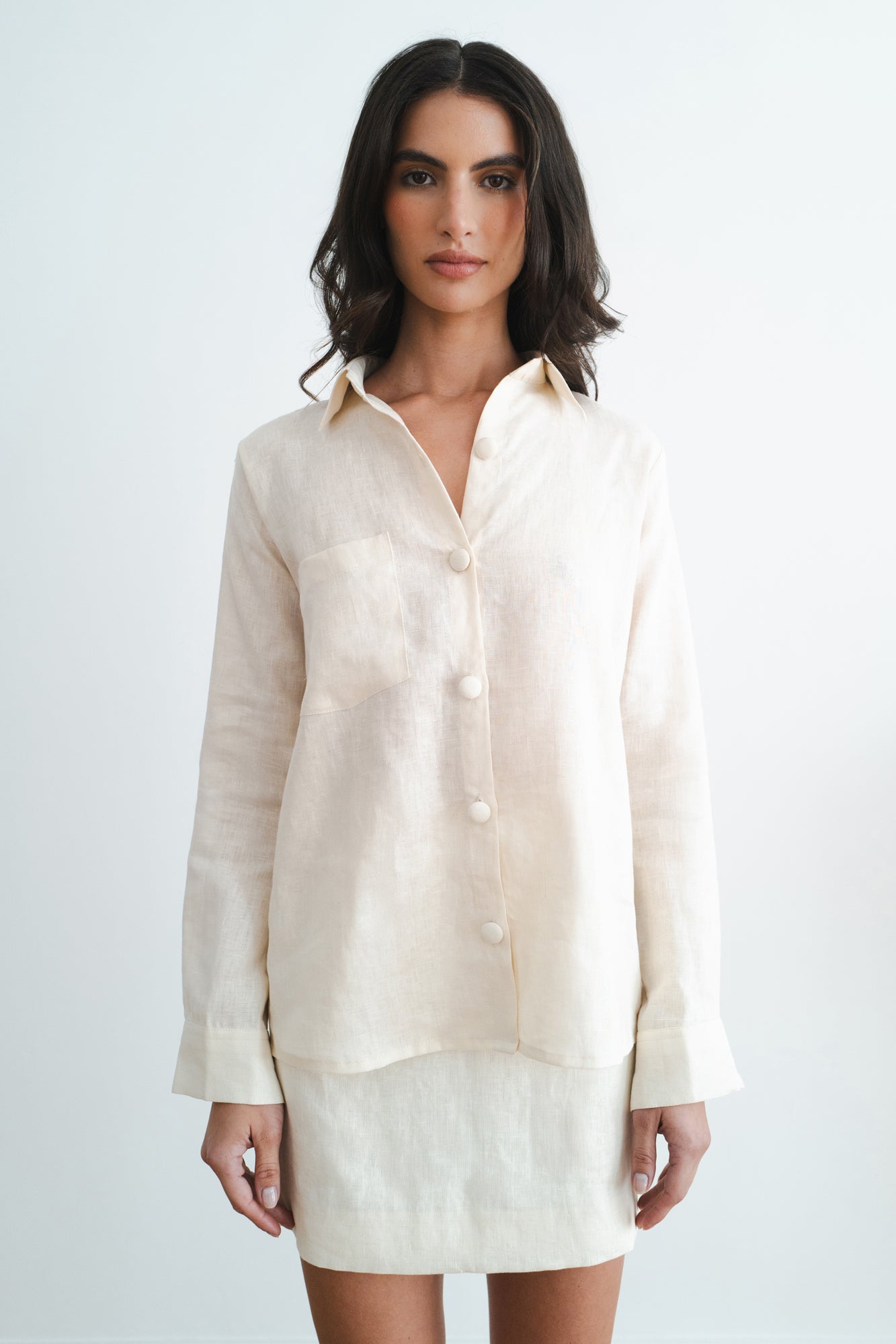 Woman wearing cream linen button-up shirt and matching mini skirt set against white background — Amara Grace | Endless UAE