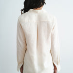 Back view of woman wearing cream linen long-sleeve shirt and shorts set against white background — Amara Grace | Endless UAE