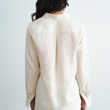 Back view of woman wearing cream linen long-sleeve shirt and shorts set against white background — Amara Grace | Endless UAE