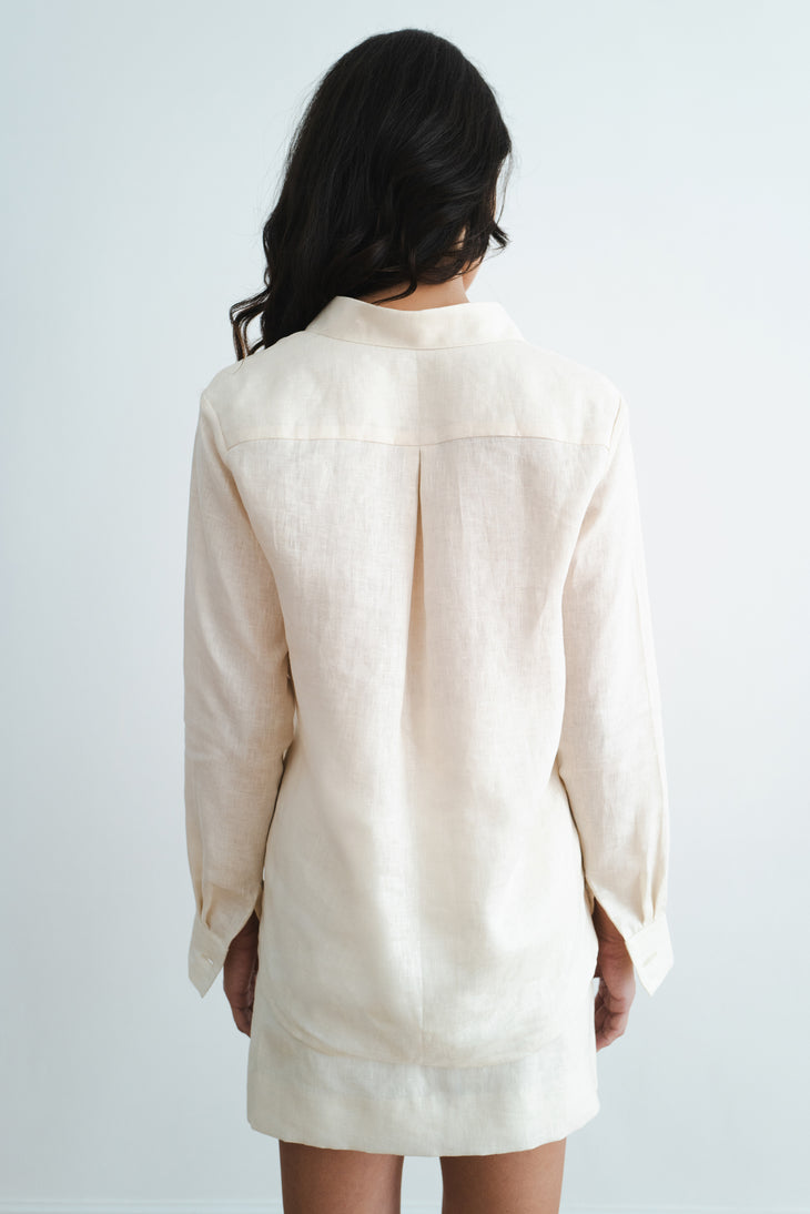 Back view of woman wearing cream linen long-sleeve shirt and shorts set against white background — Amara Grace | Endless UAE