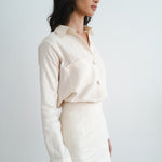 Woman wearing cream linen button-up shirt and matching mini skirt set in side profile view — Amara Grace | Endless UAE