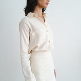 Woman wearing cream linen button-up shirt and matching mini skirt set in side profile view — Amara Grace | Endless UAE