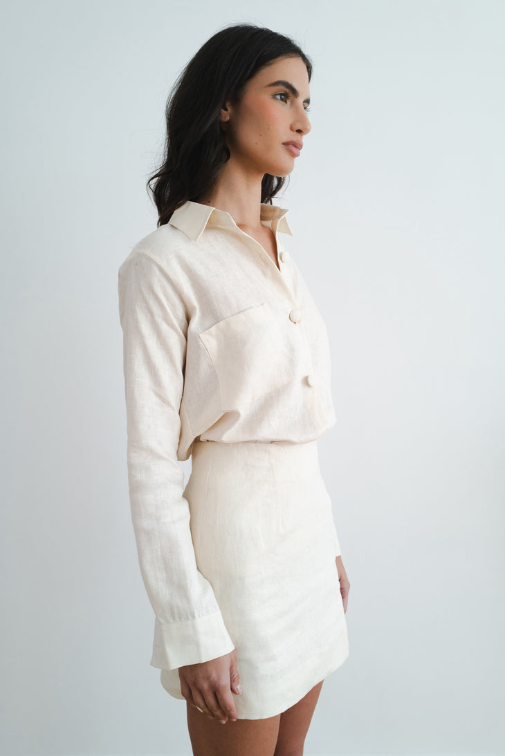Woman wearing cream linen button-up shirt and matching mini skirt set in side profile view — Amara Grace | Endless UAE