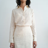 Woman wearing cream linen button-up shirt and matching mini skirt set against white background — Amara Grace | Endless UAE
