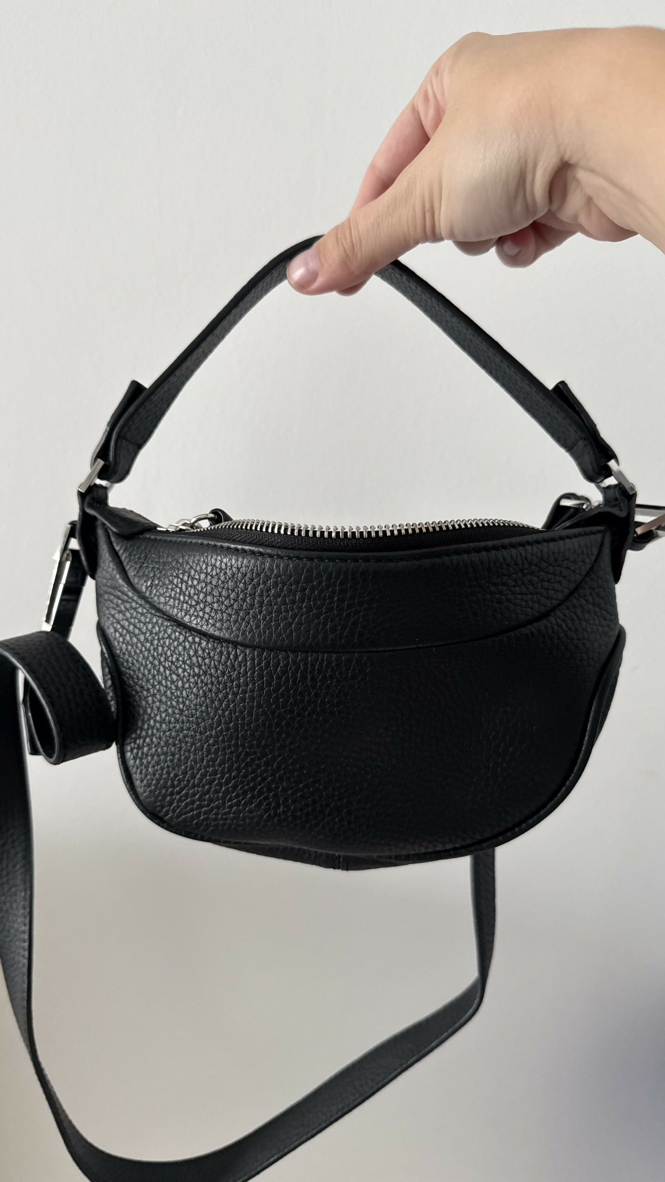 Black leather mini shoulder bag with textured finish held open to show interior — By Far | Endless UAE