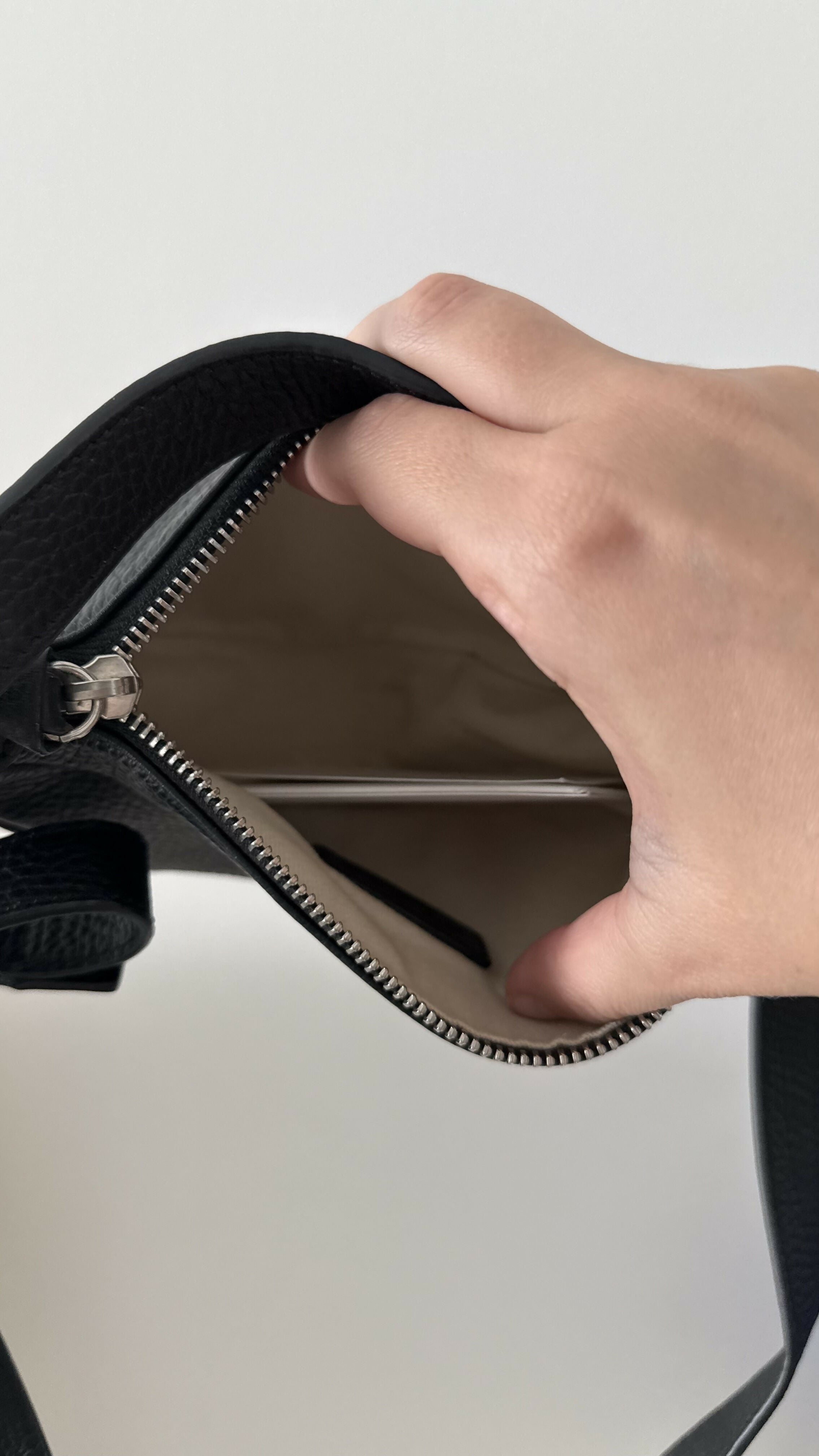 Black leather mini shoulder bag with textured finish held open to show interior — By Far | Endless UAE