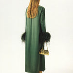 Woman wearing forest green satin midi dress with black feather cuffs and gold sandals — Sleeper | Endless UAE