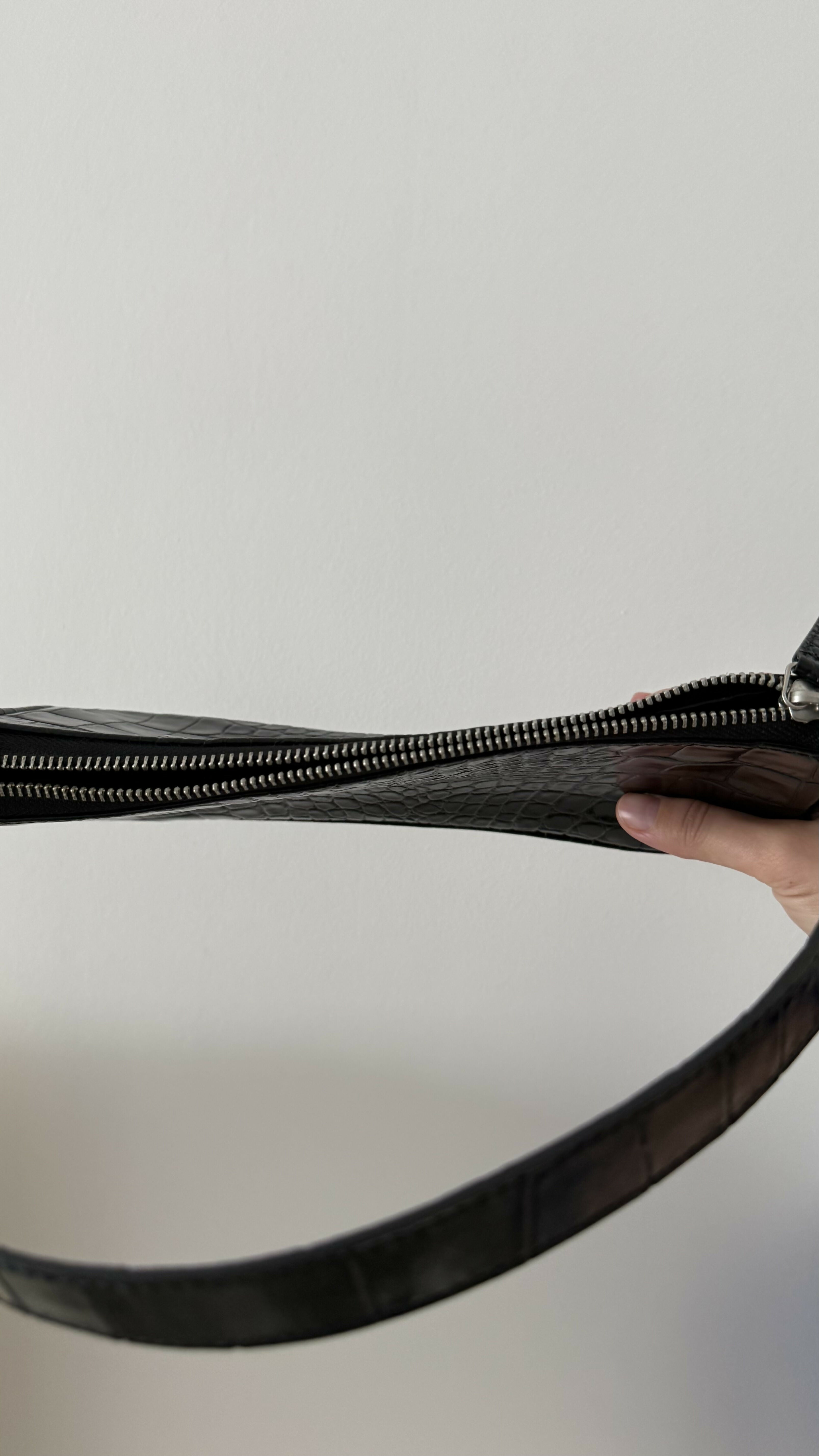 Black crocodile embossed leather shoulder bag held in hand against white background — By Far | Endless UAE