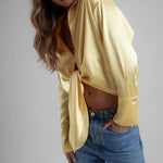 Woman wearing yellow tie-up shirt with blue jeans against gray background — By Keara | Endless UAE