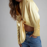 Woman wearing yellow tie-up shirt with blue jeans against gray background — By Keara | Endless UAE