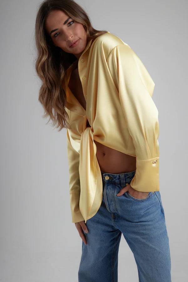 Woman wearing yellow tie-up shirt with blue jeans against gray background — By Keara | Endless UAE