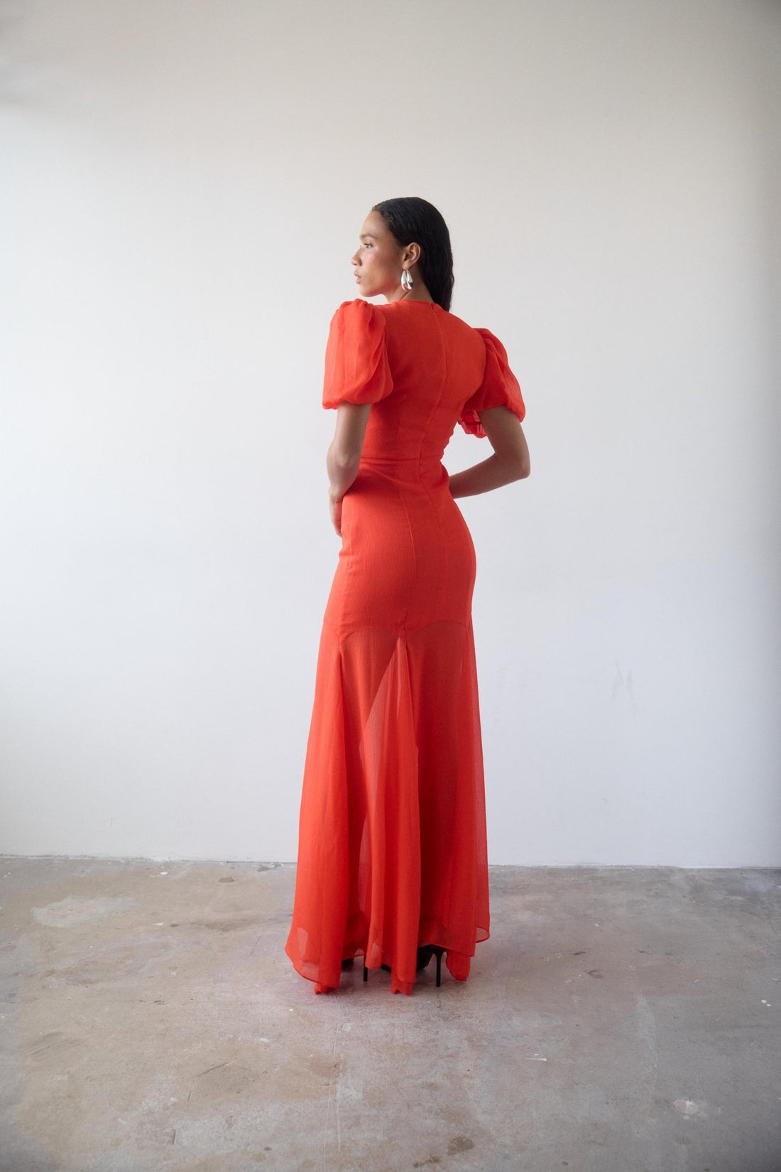 Woman wearing red crinkle chiffon maxi dress with puff sleeves — De La Vali | Endless UAE