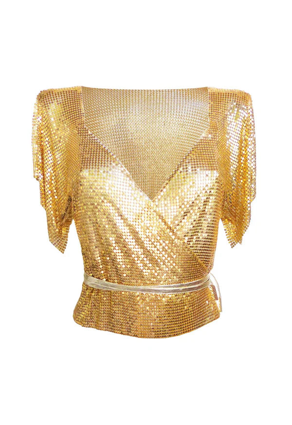 Gold sequin wrap top styled with black shorts against a rocky coastal backdrop — Isabel Moore | Endless UAE
