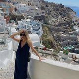 Woman wearing navy sleeveless maxi dress on Santorini terrace overlooking white buildings and sea — AG Studio | Endless UAE