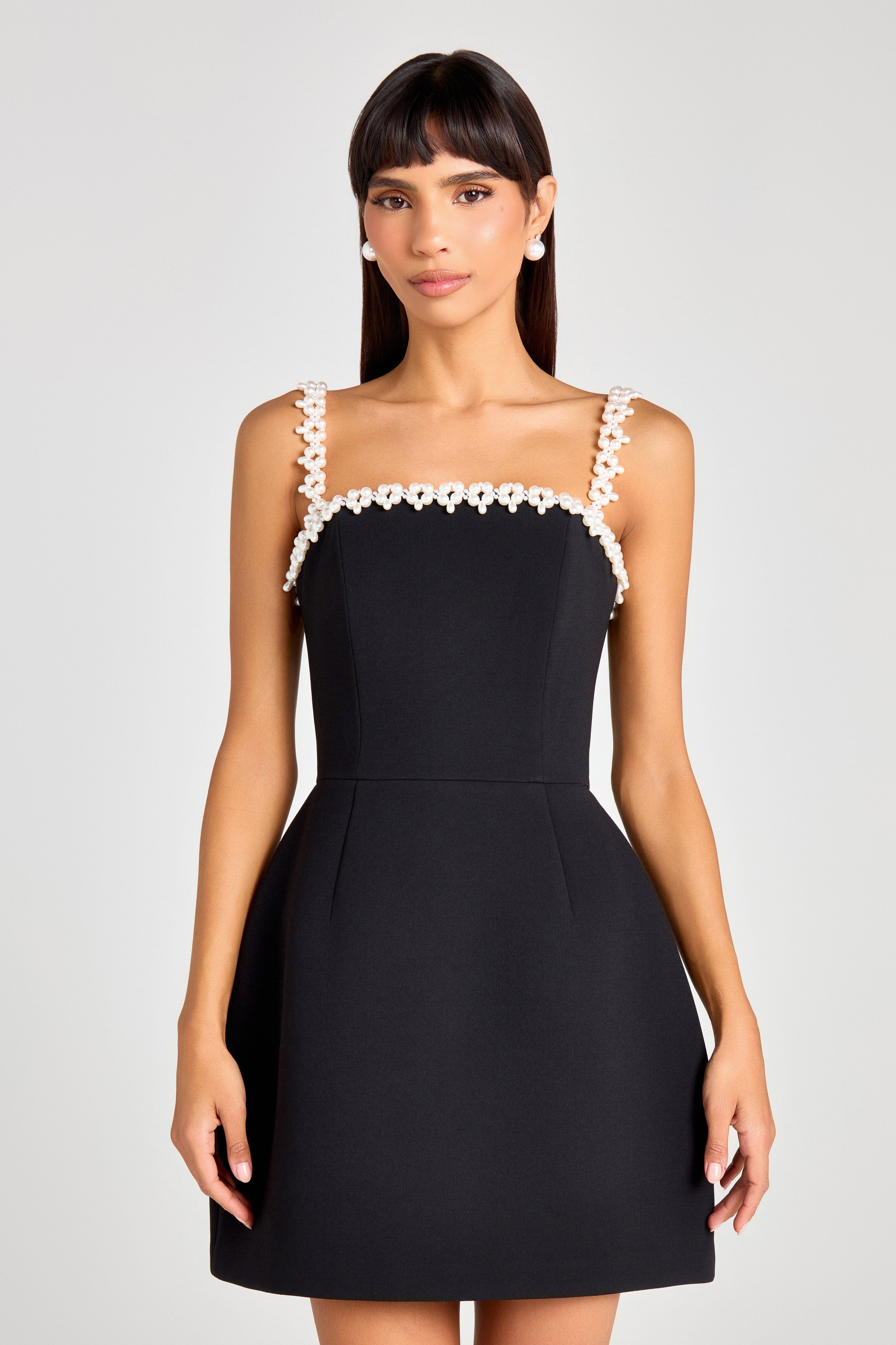 Woman wearing black sleeveless dress with white pearl neckline and straps — Nadine Merabi | Endless UAE