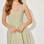 Woman wearing sage green square neck midi dress with pleated skirt and white slide sandals — Odd Muse | Endless UAE