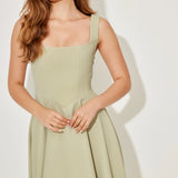 Woman wearing sage green square neck midi dress with pleated skirt and white slide sandals — Odd Muse | Endless UAE