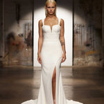 Sleek white wedding gown with plunging neckline, high leg slit, and statement crystal earrings — You&I Bridal | Endless UAE