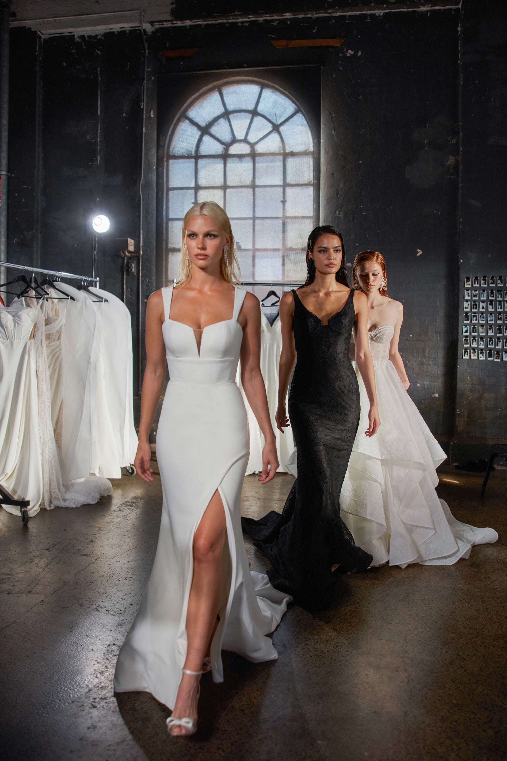 Sleek white wedding dress with plunging neckline and front slit, modeled in industrial bridal showroom — You&I Bridal | Endless UAE
