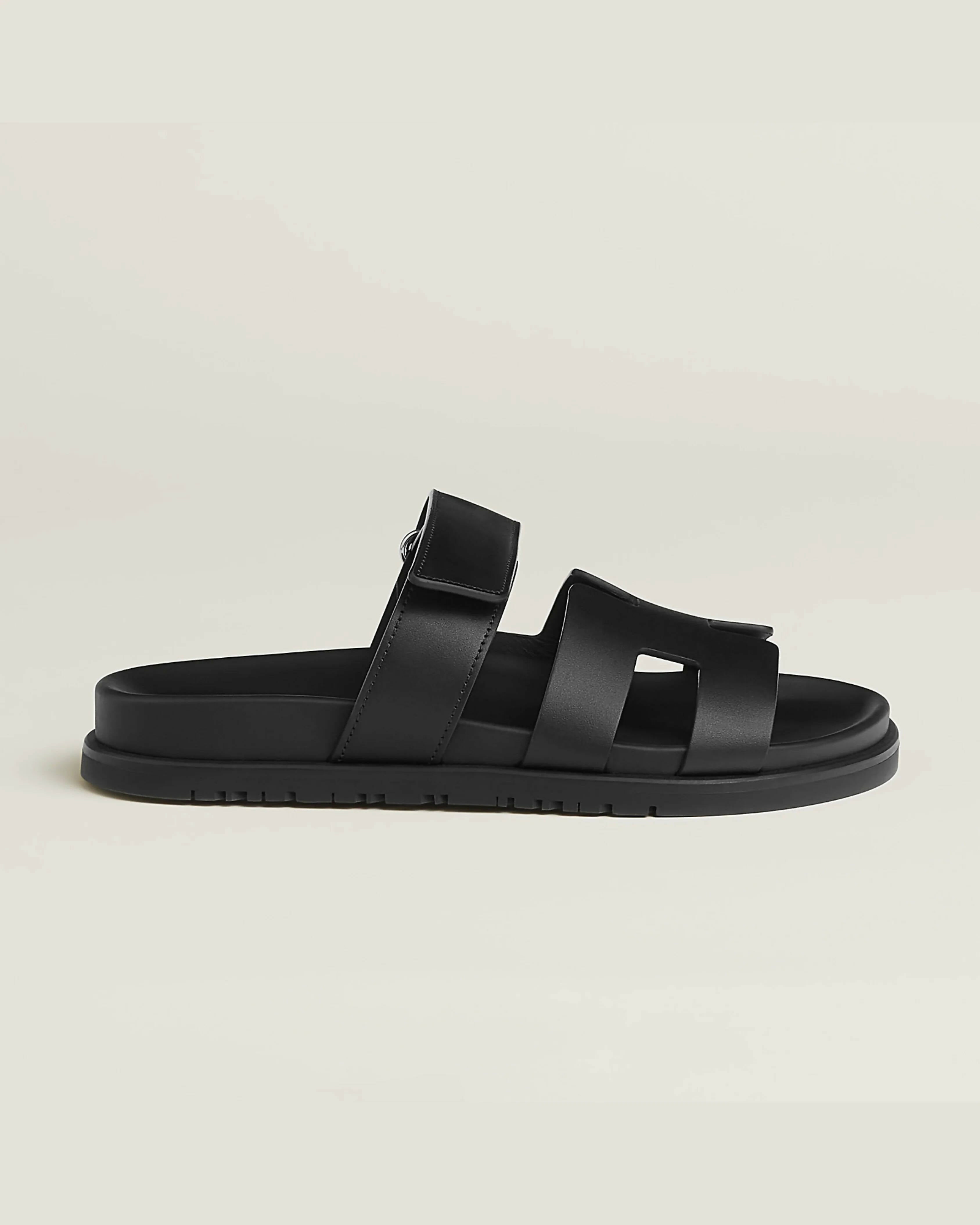 Black leather slip-on sandal with crossover straps and buckle fastening on chunky treaded sole — Hermes | Endless UAE
