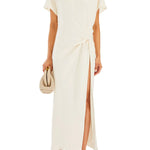 Woman wearing cream Tropez Maxi Dress with side slit, straw bag and strappy heels — SER.O.YA | Endless UAE