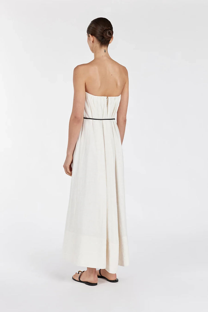 Back view of woman wearing cream strapless midi dress with black waist belt and sandals on white background — Dissh | Endless UAE