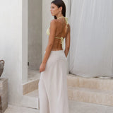Woman wearing white linen Verona Maxi Skirt with yellow bikini top in minimalist setting — Beach City | Endless UAE