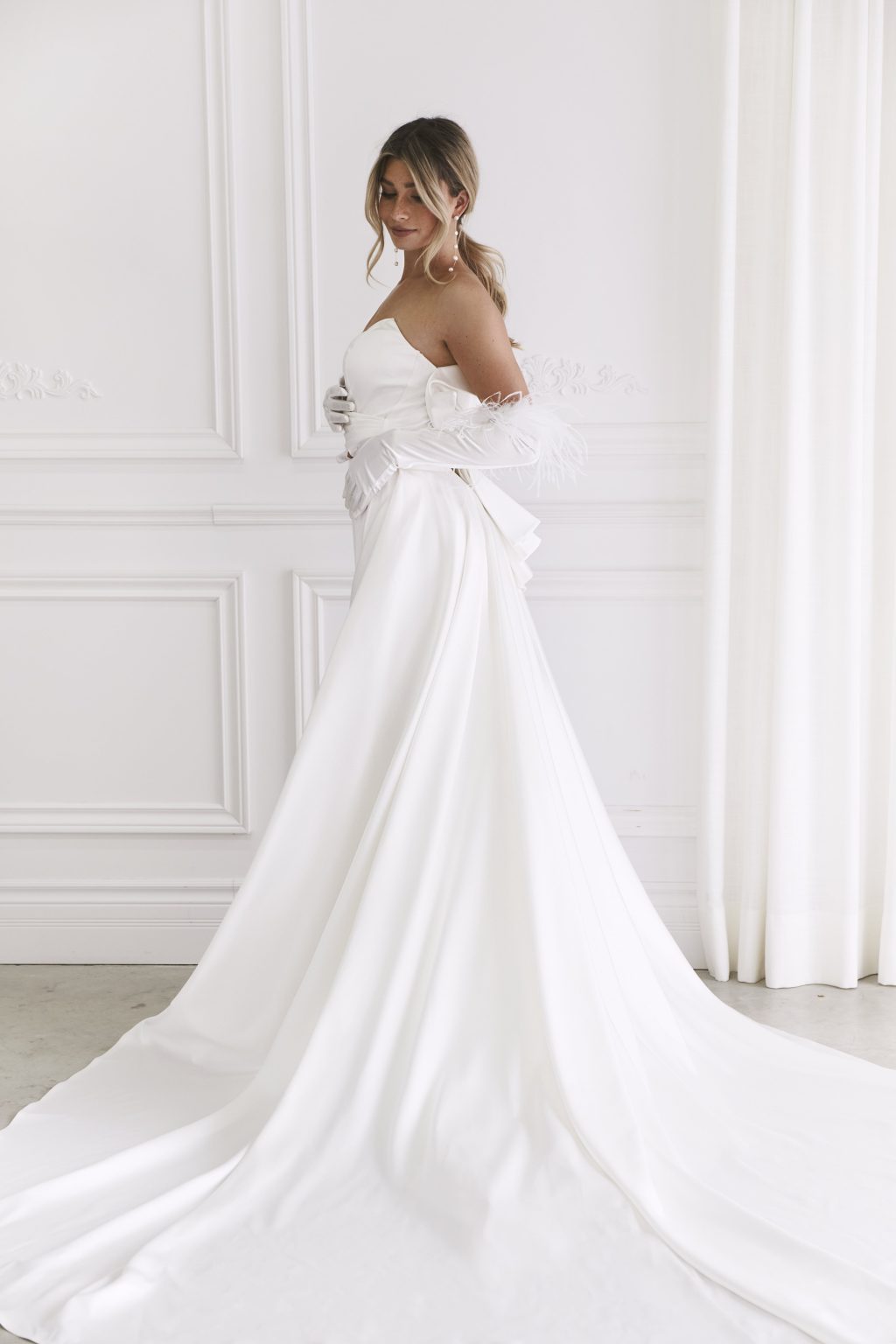 Elegant strapless white wedding gown with dramatic bow detail and flowing train — You&I Bridal | Endless UAE