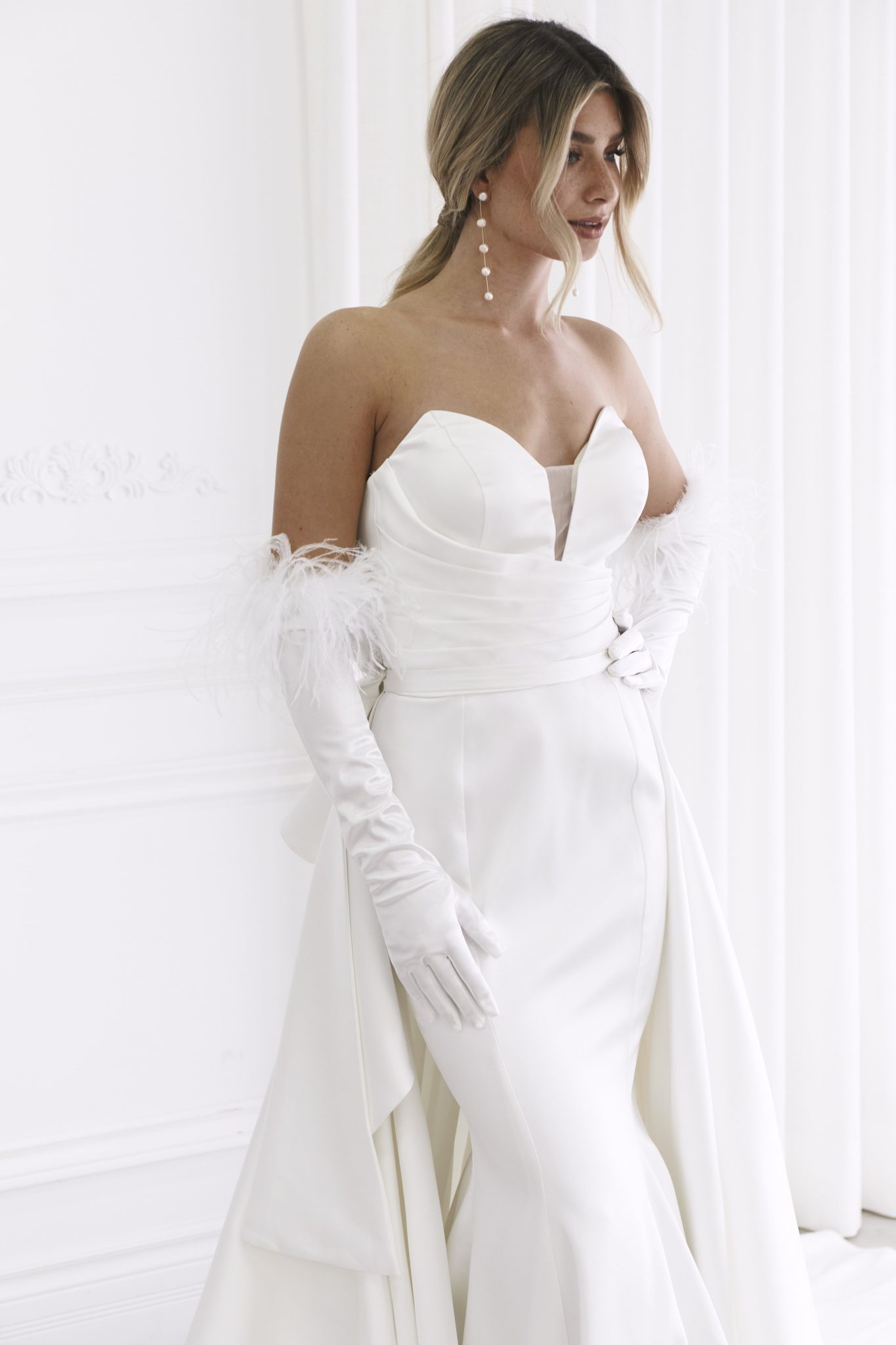 Elegant strapless wedding gown with feathered gloves and sculptural bodice in luxurious white satin — You&I Bridal | Endless UAE