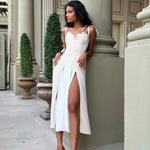 Elegant white midi dress with sweetheart neckline and high slit, modeled in classical architectural setting — Post Meridien | Endless UAE