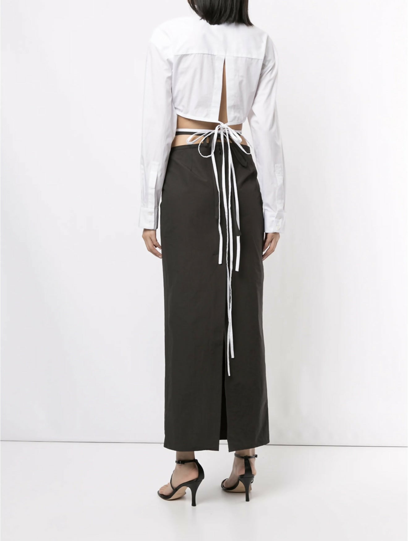 White cropped silk shirt with open back and wrap-around tie detail, paired with dark wide-leg trousers — Christopher Esber | Endless UAE