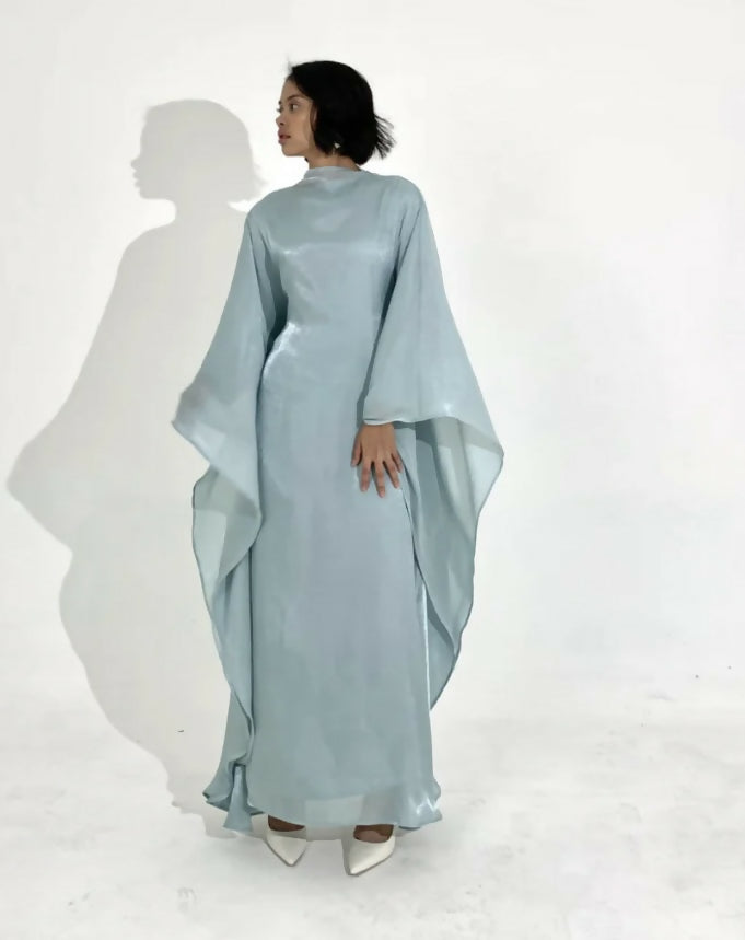 Woman wearing light blue flowing kaftan dress with draped sleeves against white background — Endless | Endless UAE