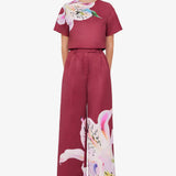 Woman wearing burgundy crop top and wide-leg floral pants with colorful lily print — Leo Lin | Endless UAE