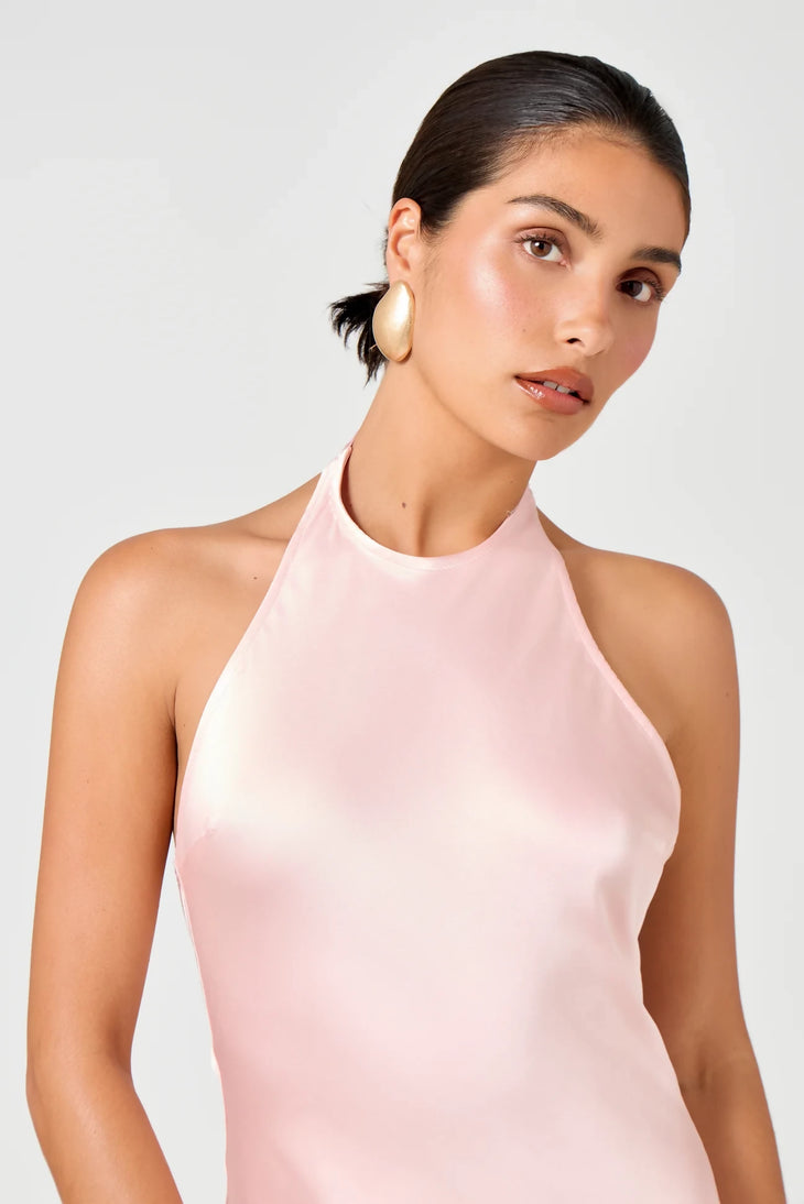 Woman wearing a light pink halter neck maxi dress with gold hoop earrings on white background — Hyphen | Endless UAE
