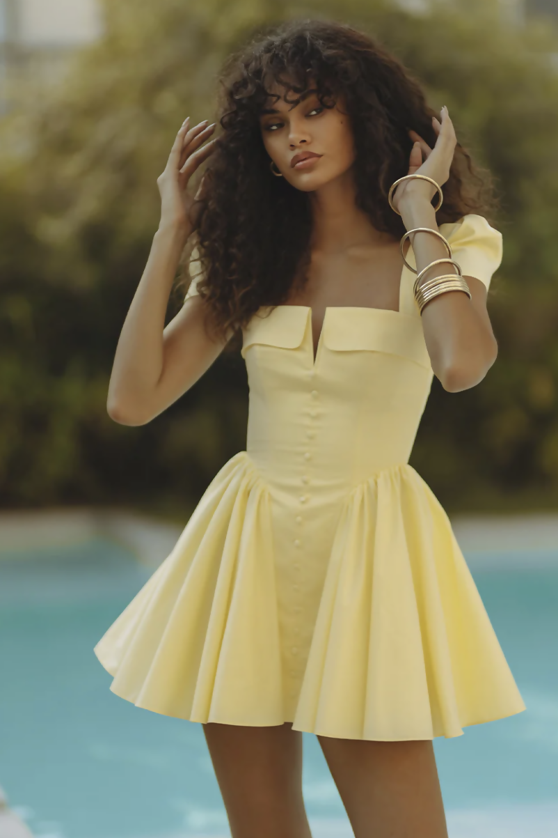 Woman wearing yellow off-shoulder mini dress with puffed sleeves by poolside — Endless | Endless UAE