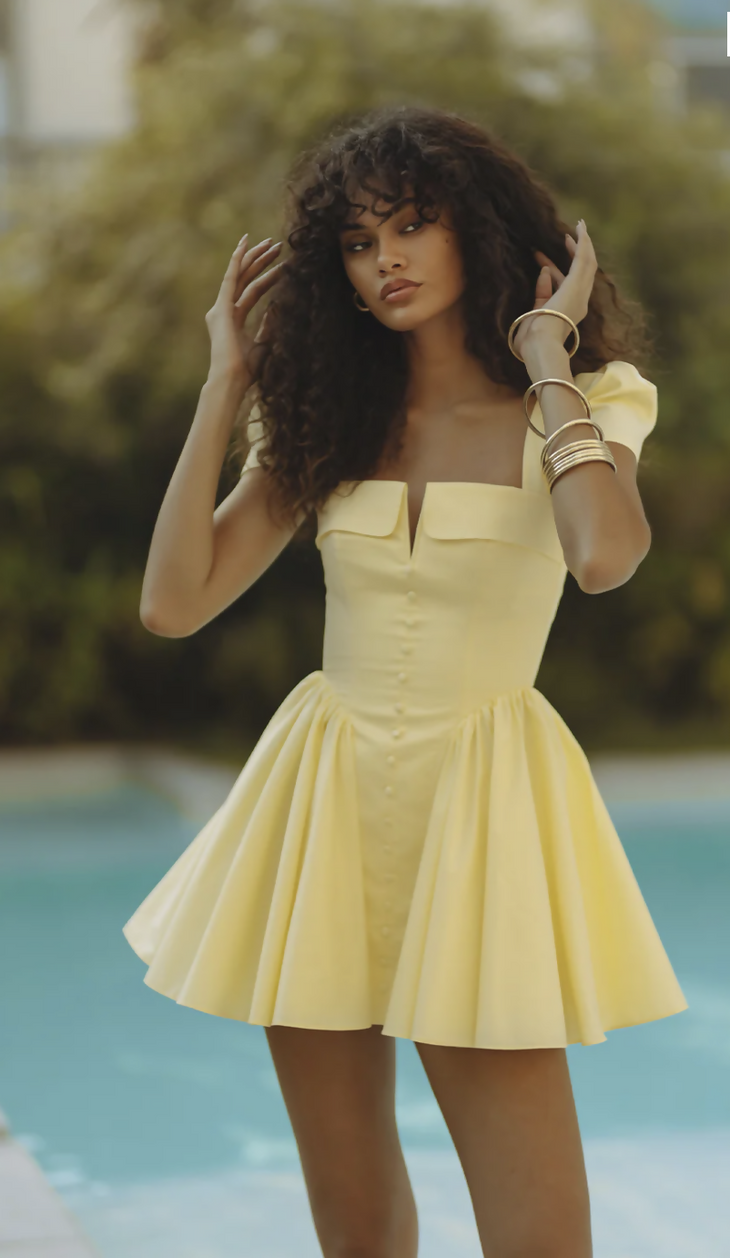 Woman wearing yellow off-shoulder mini dress with puffed sleeves by poolside — Endless | Endless UAE