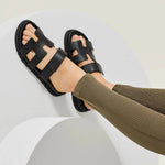 Black leather gladiator sandals with multiple straps and chunky sole, worn with olive ribbed knit pants — Hermes | Endless UAE