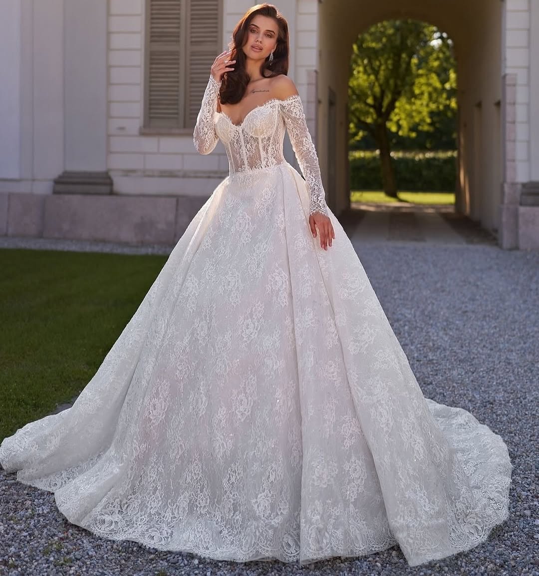 Elegant off-shoulder lace ball gown wedding dress with long sleeves and cathedral train in ivory white — Sima Couture | Endless UAE