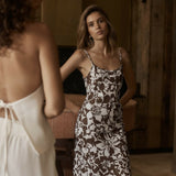 Woman wearing brown and white floral print slip dress with thin straps in elegant interior setting — Kookai | Endless UAE