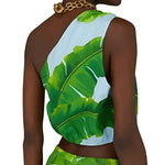 Model wearing tropical banana leaf print one-shoulder crop top with light blue background and gold chain necklace — Farm Rio | Endless UAE