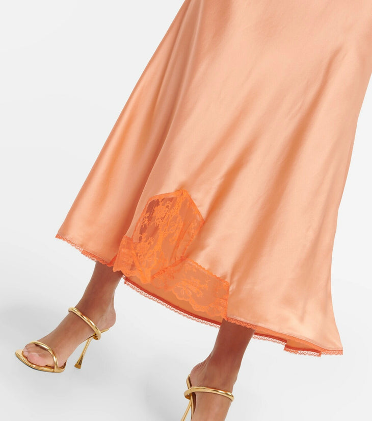Woman wearing Aries Cut Out Gown in orange peach with lace details and gold sandals — Sir The Label | Endless UAE